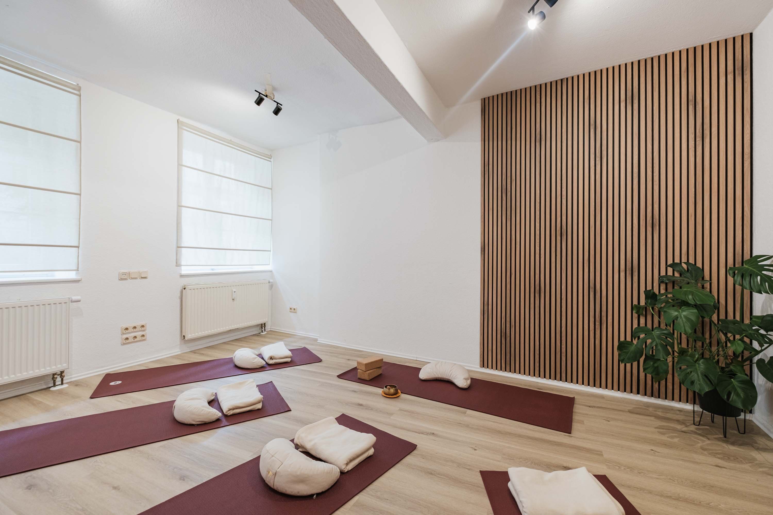 Yogamatten mit Meditationskissen vor einer Akustikholzwand
