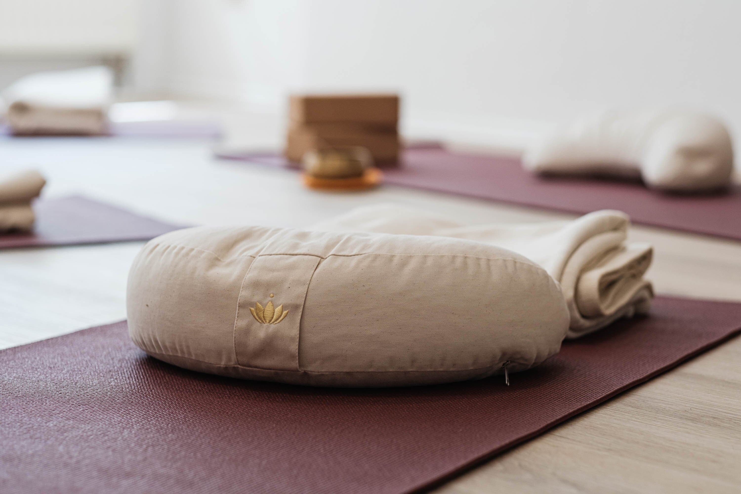 Meditationskissen mit gesticktem Lotus auf einer Yogamatte