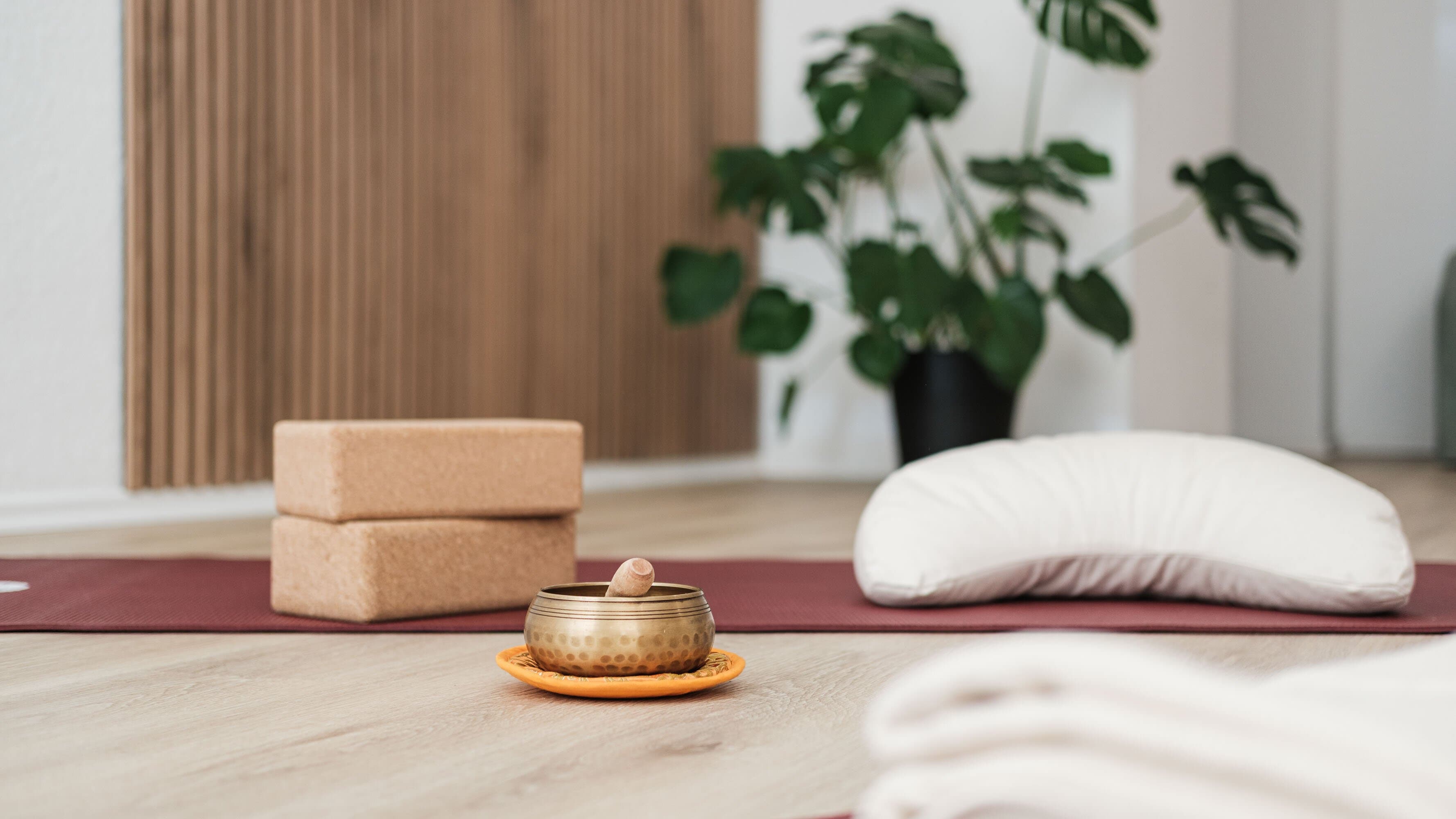 Klangschale, Kork-Blöcke und Bolster auf einer Yogamatte