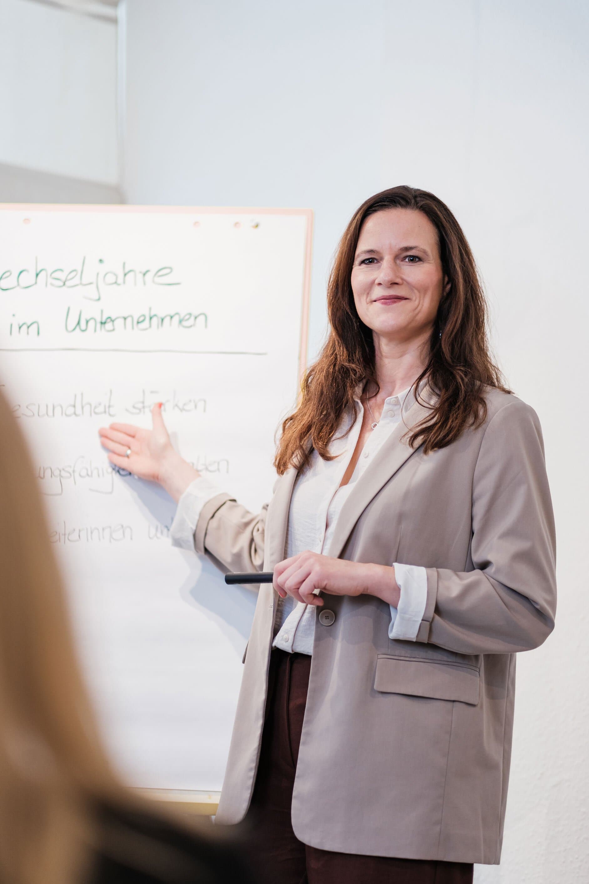 Ariane Grebenstein im beigen Blazer am Whiteboard