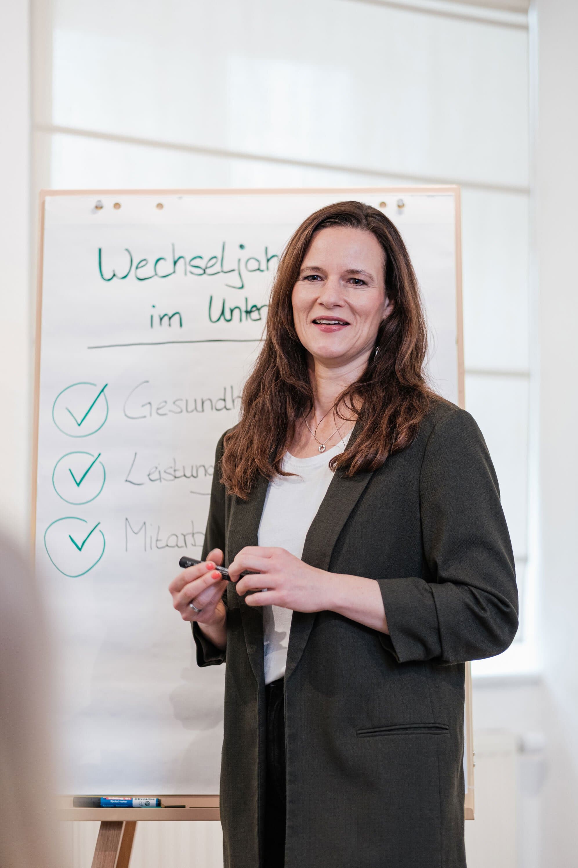 Ariane im grünen Blazer erklärt Wechseljahre am Whiteboard